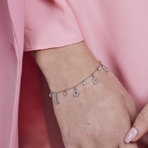 Närbild på armband i silver med berlocker som bokstaverar "Love"